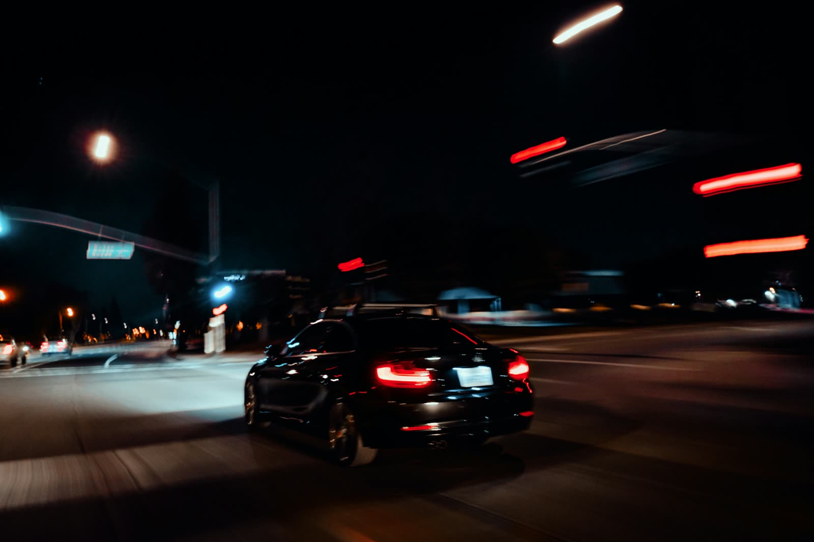 Voiture qui file dans une rue de nuit, lumières en traînées